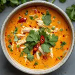 Bowl of Slow Cooker Thai Coconut Chicken Soup with fresh herbs and coconut milk